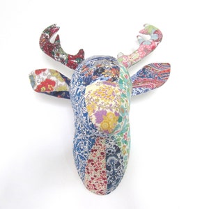 May include: A decorative deer head made of fabric with a patchwork design. The antlers and ears feature floral patterns in red, pink, and blue. The head itself is a mix of floral and paisley prints.