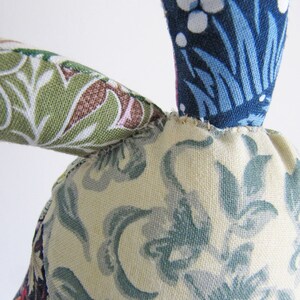 May include: A handmade fabric bunny toy with a blue, white and green floral pattern. The bunny has a long, floppy ear and a small, round body.