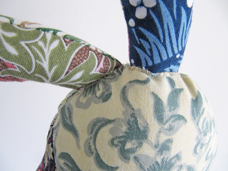 May include: A handmade fabric bunny toy with a blue, white and green floral pattern. The bunny has a long, floppy ear and a small, round body.