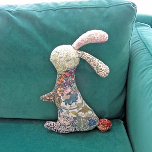 May include: A patchwork fabric bunny toy with a floral pattern, sitting on a teal sofa.