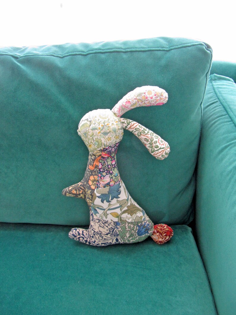 May include: A patchwork fabric bunny toy with a floral pattern, sitting on a teal sofa.