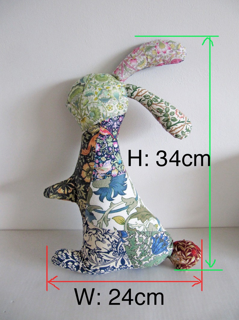 May include: A patchwork fabric bunny toy with a long, floppy ear. The bunny is sitting on a white surface and is 34 cm tall and 24 cm wide.
