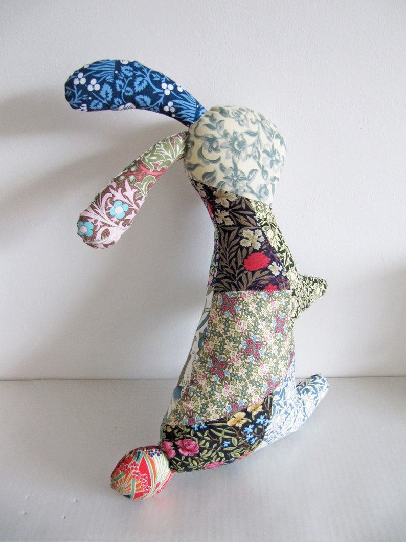 May include: A patchwork bunny toy with a long, floppy ear. The bunny is made from a variety of floral fabrics in shades of blue, green, red, and yellow.