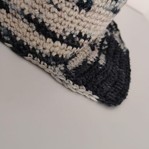 Primo piano di un cappello all'uncinetto. Il cappello ha una lavorazione semplice. La tesa è visibile e rifinita.
