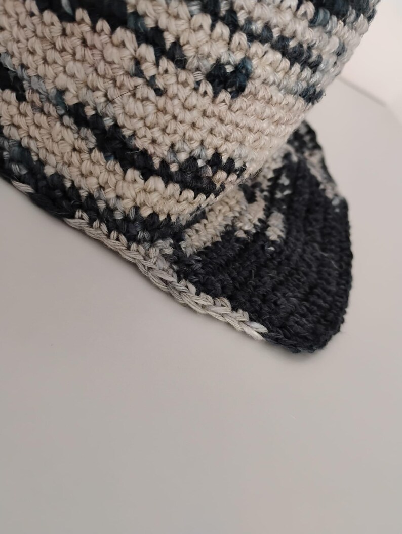 Primo piano di un cappello all'uncinetto. Il cappello ha una lavorazione semplice. La tesa è visibile e rifinita.