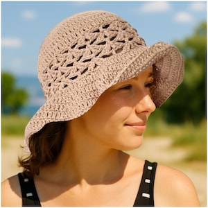 Può includere: Un cappello da sole all'uncinetto marrone chiaro con una tesa larga. Il cappello presenta un design traforato sulla corona e una tesa piena. Il cappello è realizzato in un filato morbido e strutturato, adatto per l'esterno.