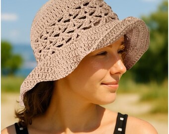 May include: A light brown crochet sun hat with a wide brim. The hat features an openwork design on the crown and a solid brim. The hat is made of a soft, textured yarn and is suitable for outdoor wear.