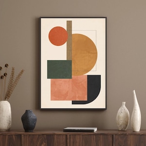 Könnte beinhalten: Abstrakter Kunstdruck mit geometrischen Formen in Orange, Grün, Schwarz und Beige auf cremefarbenem Hintergrund. Das Kunstwerk ist in Schwarz gerahmt und über einem Holzschrank mit dekorativen Vasen ausgestellt.