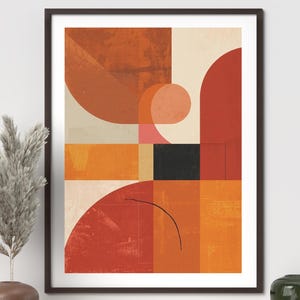 May include: Abstract art print in a black frame. The artwork features geometric shapes in shades of orange, red, and beige, with a black square and a curved black line. The print is displayed on a wooden shelf with decorative items.