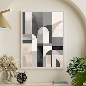 Könnte beinhalten: Gerahmter abstrakter Kunstdruck mit geometrischem Design in Grautönen. Das Kunstwerk, das Formen in Grau, Schwarz und Beige zeigt, wird auf einem Holzregal präsentiert. Eine Uhr, eine Vase und Pflanzen vervollständigen die moderne Inneneinrichtung.