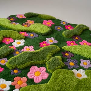 May include: A tufted rug featuring a deep green background with raised, textured lime green organic shapes and a scattered pattern of multi-colored flowers in shades of pink, white, purple, and orange, each with a bright yellow center.