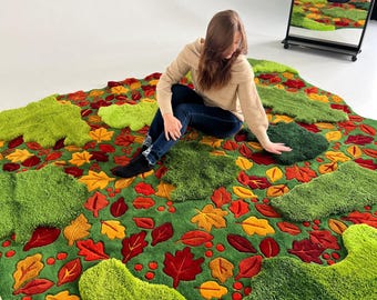 May include: A large, green rug with a leaf design in shades of red, orange, and yellow. The rug has a textured, plush appearance, with raised leaf shapes and a green background. The rug is on a white surface.
