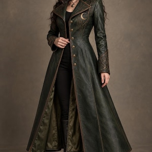 May include: A long, dark green coat featuring a high collar, brown trim, and a series of brass-coloured buttons down the front. The chest area displays an embroidered crescent moon and branch design, with matching embroidery on the sleeve cuffs.