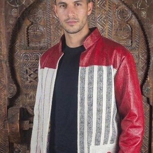 May include: A jacket featuring a red textured upper section and sleeves, combined with a cream-coloured body panel displaying vertical black stripes. A single red heart patch is stitched onto the lower front pocket area of the garment.