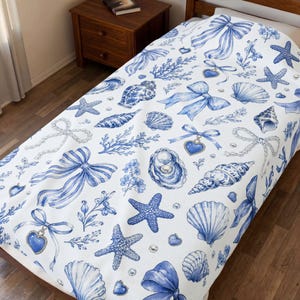 May include: White bedspread with a blue watercolor design featuring seashells, starfish, bows, and heart-shaped pendants. The nautical-themed pattern includes pearls and floral accents, creating a coastal aesthetic.
