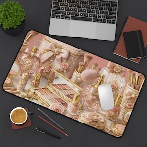 Könnte beinhalten: Eine rechteckige Schreibtischunterlage mit einem Druckdesign aus verschiedenen Make-up-Artikeln in Rosa- und Goldtönen, darunter Parfümflakons, eine Palette, Lippenstift, Nagellack und Pinsel, mit einer weißen Computermaus auf der Oberfläche.
