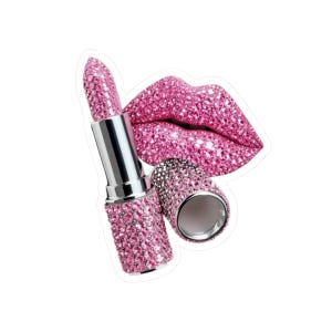 Könnte beinhalten: Eine Lippenstift-Hülse und die passende Kappe, die vollständig mit funkelnden rosa Kristallen bedeckt sind, neben einem Paar voller, leicht geöffneter Lippen, die ebenfalls komplett mit denselben leuchtend rosa, reflektierenden Kristallsteinen besetzt sind.