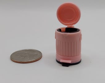 Pequeño bote de basura rosa con tapa que se abre