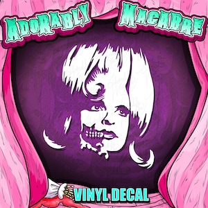 Puede incluir: Una calcomanía de vinilo con una ilustración estilizada del rostro de una mujer con una apariencia de calavera en un lado. La imagen está sobre un fondo morado oscuro, enmarcada por cortinas rosas, e incluye el texto "ADORABLY MACABRE" y "VINYL DECAL".