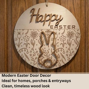 Könnte beinhalten: Runder hölzerner Ostertürschild mit den ausgeschnittenen Worten „Frohe Ostern“ oben. Die untere Hälfte zeigt ein Blumenmuster und eine Hasen-Silhouette. Zum Aufhängen ist eine Juteschnur befestigt.