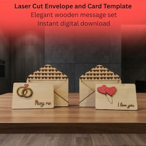 Könnte beinhalten: Laserschnitt-Umschlag- und Kartenset aus Holz. Das Set enthält zwei Umschläge und zwei Karten mit den Sätzen "Marry me" und "I love you". Die Umschläge sind mit Herz-Ausschnitten versehen. Der Text "Laser Cut Envelope and Card Template" steht oben.