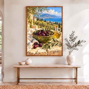 May include: A framed wall art print depicting a Mediterranean coastal landscape with a green bowl filled with dark purple olives, a glass cruet of golden olive oil, and olive branches resting on a stone surface against a blue sea and sky.
