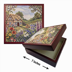 May include: A square wooden box with a dark mahogany finish featuring a textured lid depicting a thatched-roof cottage surrounded by a vibrant garden of poppies, daisies, and bluebells. The box measures 7 inches in width as indicated.