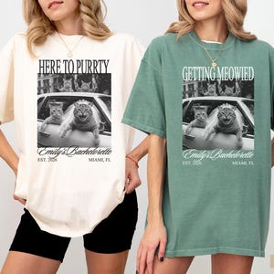 Pu&ograve; includere: T-shirt avorio e verde chiaro con grafica in bianco e nero di gatti in auto. La maglietta avorio dice "HERE TO PURRTY" e la maglietta verde chiaro dice "GETTING MEOWIED". Entrambe le magliette hanno stampato "Emily's Bachelorette" e "Miami, FL".