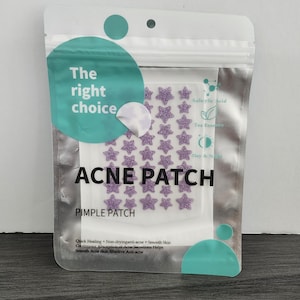 May include: A clear plastic package containing star-shaped acne patches. The package has the words "The right choice" and "ACNE PATCH" printed on it. The patches are purple and glittery. The package also lists ingredients and benefits.
