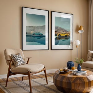 May include: Two framed art prints featuring vintage sports cars, one teal and one yellow, reflected in water. The prints are displayed above a mid-century modern chair and a geometric coffee table, creating a stylish living room scene.