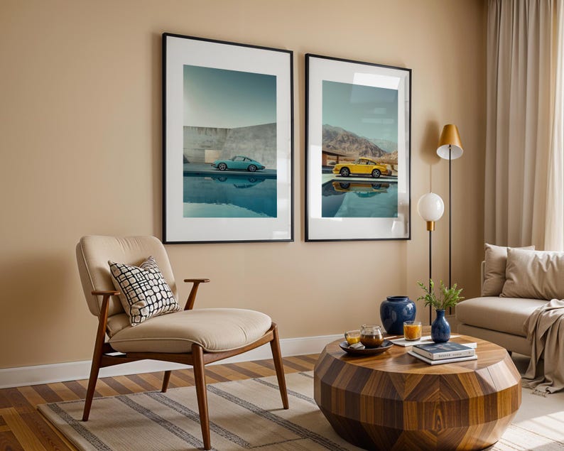 May include: Two framed art prints featuring vintage sports cars, one teal and one yellow, reflected in water. The prints are displayed above a mid-century modern chair and a geometric coffee table, creating a stylish living room scene.