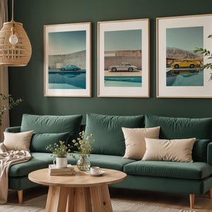 May include: Three framed art prints featuring vintage cars in teal, silver, and yellow, each parked near a pool. The prints are displayed above a green velvet sofa with beige pillows, creating a stylish living room decor.