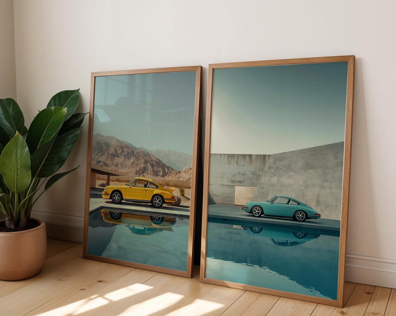 May include: Two framed art prints featuring vintage sports cars. One print shows a yellow car near mountains, the other a teal car near a pool. Both prints have wooden frames and are displayed on a wooden floor.