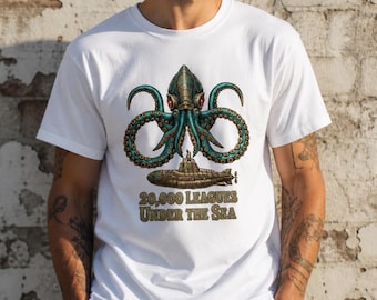 Puede incluir: Camiseta blanca con una ilustración detallada de un pulpo con tentáculos turquesa y un submarino. El texto "20.000 Leguas de Viaje Submarino" está impreso debajo en un estilo vintage.