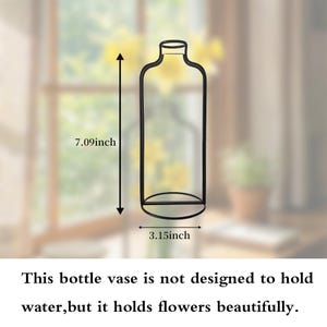 Op de afbeelding: Zwarte metalen flesvaas, 18 cm hoog en 8 cm breed. De vaas is ontworpen om bloemen in te zetten. De tekst op de afbeelding luidt: "Deze flesvaas is niet ontworpen om water vast te houden, maar hij houdt bloemen prachtig."
