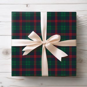 May include: A wrapped gift with a plaid pattern in navy blue, green, and red. The gift is tied with a cream-colored satin ribbon and bow. The wrapping paper has a classic tartan design.