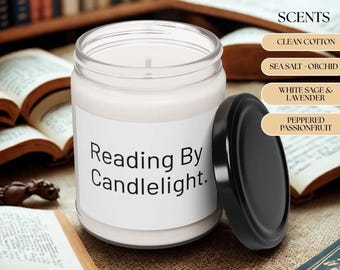 May include: A white candle in a clear glass jar with a black lid. The label reads "Reading By Candlelight." The candle is surrounded by open books. Scent options include Clean Cotton, Sea Salt + Orchid, White Sage & Lavender, and Peppered Passionfruit.