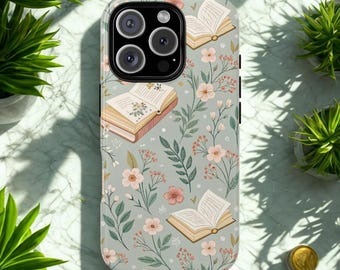 May include: A phone case with a floral and book design. The case features a light gray background with illustrations of open books, pink flowers, and green leaves. The case has a glossy finish and a camera cutout.