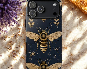 May include: A black smartphone case featuring a golden bee design. The bee has detailed wings and a striped abdomen. The case also has gold floral accents and a black camera module.