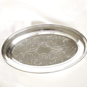 Könnte beinhalten: Eine ovale silberne Servierplatte mit einem gravierten floralen Muster. Die Platte hat einen erhöhten Rand und eine polierte Oberfläche. Die dekorative Platte eignet sich zum Servieren oder Ausstellen.