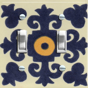 May include: A light switch plate with a decorative design featuring a blue and yellow pattern. The plate has two toggle switches labeled "ON".