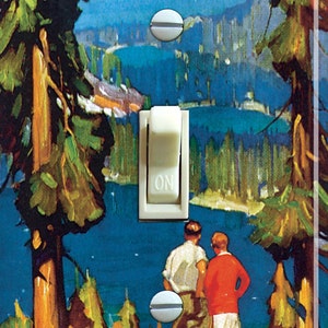 May include: A light switch cover featuring a vintage illustration of Lake Tahoe, California. The image shows a scenic view of the lake with mountains in the background and two people standing on a hill overlooking the water. The text "Lake Tahoe" is written in a decorative font at the top of the image.