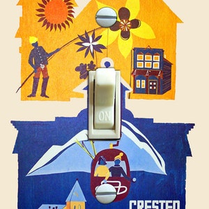 May include: A vintage-style illustration of a light switch with the word "ON" printed on it. The switch is surrounded by a colourful image of a town with a mountain in the background. The text "CRESTED BUTTE COLORADO" is printed below the image.