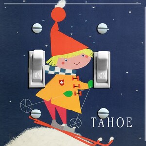 May include: A light blue light switch plate featuring a cartoon illustration of a skier wearing a red hat, yellow jacket, and white trousers. The skier is holding ski poles and is skiing down a snowy hill. The words "TAHOE" are printed in white letters on the bottom right corner of the plate.
