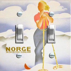 May include: A vintage-style light switch plate featuring a skier in a blue and red outfit with a yellow ski pole. The plate has the text "NORGE SKISPORTENS HJEMLAND" in gold lettering.