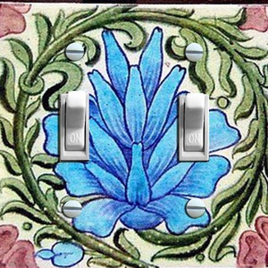 May include: A light switch cover with a floral design. The design features a blue flower with green leaves and vines on a white background. The switch cover has two toggle switches labeled "ON".
