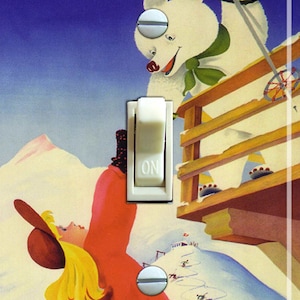 May include: A light switch cover featuring a vintage illustration of a girl in a red coat and a white bear on skis. The text "Lake Tahoe" is written in red and yellow letters at the top of the image.