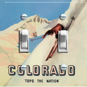 May include: A vintage-style light switch plate featuring a skier on a mountain with the text "COLORADO" and "TOPS THE NATION".