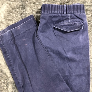 May include: A pair of navy blue pants with a button and zipper closure, belt loops, and a single back pocket. The pants are made of a sturdy fabric and show some wear.