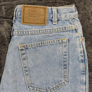 May include: Light blue denim jeans with a classic five-pocket design. The back features a single pocket and a brown leather patch with the text "Code Bleu" and "Nordstrom". The jeans have a straight leg cut.